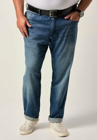 Blå denimjeans, avslappnad passform, rak benform med lätt blekning, uppkavlade muddar, bärs med ett svart bälte och vita sneakers.