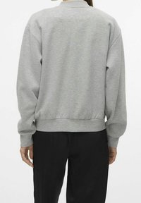 Szara bluza z okrągłym dekoltem, długimi rękawami i ściągaczem na dole. Tkanina wydaje się miękka i lekko teksturowana, odpowiednia do noszenia na co dzień.