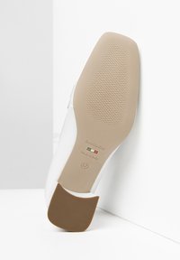 Zapato de tacón alto blanco con suela de goma marrón, con un patrón de agarre texturizado y logo estampado, tamaño 37, fabricado en Italia.