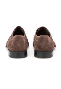 Chaussures en daim brun avec une texture lisse, bouts ronds et semelles en caoutchouc noir contrastantes ; détails de couture minimal sur la tige.