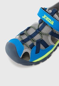Sandală albastră și gri cu plasă superioară, curea ajustabilă, design perforat, capac de cauciuc pentru degete și detalii de accent verzi. Potrivită pentru îmbrăcămintea activă.