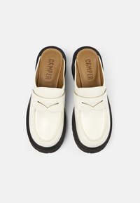 Scarpe slip-on bianche in pelle con punta arrotondata, suola in gomma nera e sottile cucitura decorativa. L'interno presenta una soletta imbottita marrone.
