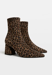 Bottes chevilles à imprimé léopard en tissu doux, dotées d'une pointe effilée et d'un talon bloc pour la stabilité, avec des accents noirs contrastants.