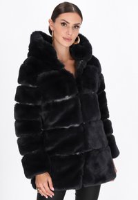Sort faux fur pufferjakke med hætte, der har et quiltet design, blød tekstur og frontknaplukning. Fremhævet af brede ærmer.