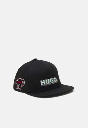 Casquette de baseball noire à visière plate avec logo multicolore "HUGO" à l’avant et silhouette rouge de chameau avec texte "HUGO" sur le panneau latéral.