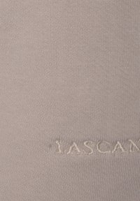 Tessuto lavorato a maglia grigio chiaro con una sottile texture, con lettering ricamato parzialmente visibile vicino al fondo.