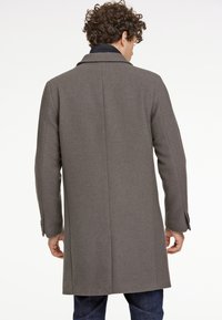 Cappotto di lana grigio con una vestibilità su misura, grande colletto e polsini con bottone. Texture liscia, design lungo fino al ginocchio con una finitura pulita.