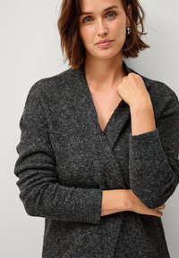 Dunkelgrauer strukturierter Cardigan mit Wickeldesign und langen Ärmeln. Auffällige Details sind die weiche Textur und der tiefe V-Ausschnitt.