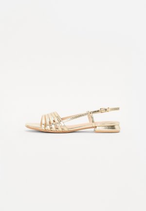 Sandales gladiateurs dorées avec des brides horizontales, un talon plat et une sangle de cheville. Texture lisse et brillante avec une finition métallique.