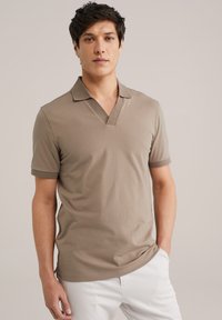 Beige poloshirt met een V-hals en korte mouwen, gemaakt van een zachte stof. Heeft contrasterende randen op de kraag en de mouwen. Past nauwsluitend.