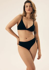 Czarny zestaw bikini z trójkątnym biustonoszem na regulowanych rami�ączkach i wysokim stanem majtek, wykonany z gładkiego materiału o matowym wykończeniu.