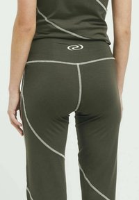 Zöld sport leggings, kontrasztos szürke varrással, illeszkedő derékkal, melyen kör alakú logó található, valamint sima, elasztikus anyagból készült.