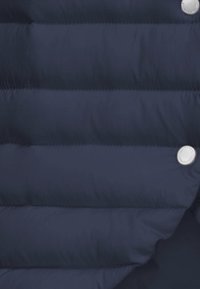 Navyblaue Steppjacke mit gestepptem Design, glänzendem Stoff und runden Metalldruckknöpfen. Strukturiert Oberfläche mit auffälligen Nahtlinien.