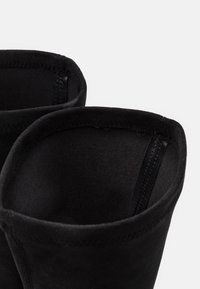 Bottes chevilles en daim noir avec une doublure intérieure lisse, une ouverture arrondie et des coutures nettes le long du bord pour une durabilité optimale.