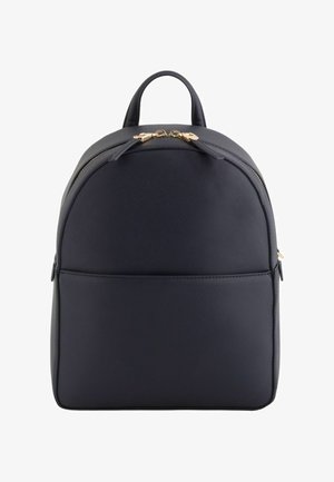 Mochila negra compacta con material texturizado, parte superior redondeada, bolsillo frontal y dos tiradores de cremallera dorados en el compartimento principal.