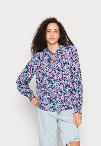 Blusa de manga longa em azul-marinho com padrão floral, apresentando flores rosas e azuis, decote franzido e punhos elásticos. Feita de um tecido suave.