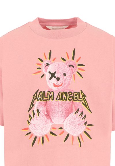 Różowa bawełniana koszulka z grafiką pluszowego misia w opasce na oku, otoczonego promieniami oraz tekstem "Palm Angels" napisanym pogrubioną czcionką.
