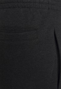 Svarta sweatpants i mjukt, strukturerat tyg, med en liten bakficka och elastisk midja. Enkel design utan mönster.