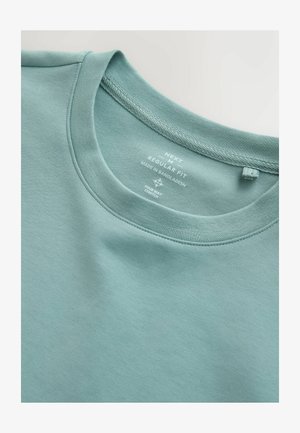 Maglietta a maniche corte colore verde acqua chiaro, con scollo rotondo, realizzata in tessuto elasticizzato. Presenta etichette sul retro che indicano marca e vestibilità.