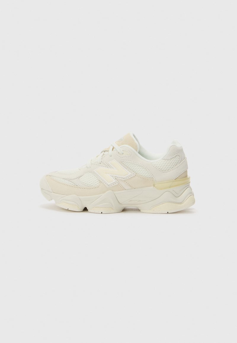 Chaussure de sport blanche avec des matériaux en maille et en cuir, forme arrondie, semelle épaisse, accents texturés et sous-tons beiges subtils.