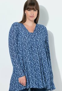 Niebieska bluzka w kwiatowy wzór z długim rękawem i dekoltem w serek, charakteryzująca się luźnym krojem i marszczeniem. Wykonana z lekkiego materiału o gładkiej fakturze.