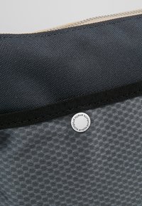 Szary materiałowy worek o teksturowanej powierzchni, z ciemnym zamkiem błyskawicznym i okrągłą etykietą z logotypem "anello".