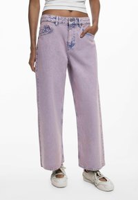 Jeans de pierna ancha de color púrpura claro, hechos de denim, con una cintura alta, manchas deslavadas y el clásico estilo de cinco bolsillos. Cierre tradicional con botón y cremallera.