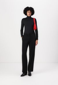 Melna turtlenecka blūze, melni piegriezti bikses un melnas potītes zābaki. Sarkana rokas soma kā akcenta elements. Gluda tekstūra, pieguļoša augšdaļa, taisnas bikses.