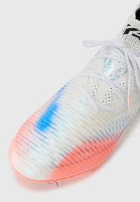 Weißer Sport-Schuh mit strukturiertem Obermaterial, Farbverlauf-Muster in Blau- und Rosatönen und weißen Schnürsenkeln. Das Design legt den Fokus auf Leistung.