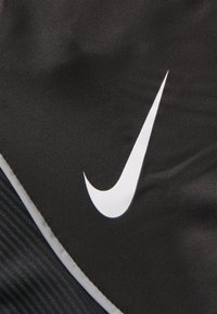 Sac de sport en tissu noir arborant un logo Nike Swoosh blanc bien en vue. La texture est lisse, avec des accents gris contrastants le long des bords.