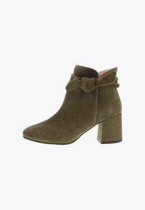 Grüne Wildleder-Stiefeletten mit spitzer Zehenpartie, Blockabsatz und einer dekorativen geflochtenen Schleife am Knöchel. Glatte Textur und minimalistische Nähdetails.