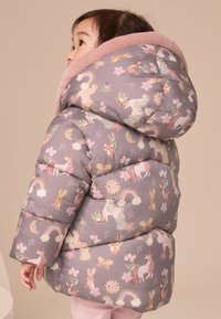 Doudoune avec un col en fausse fourrure rose pâle, base grise avec des motifs colorés d'animaux et floraux, et un design matelassé pour l'isolation.