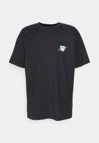 Camiseta de algodón negra de manga corta, con un pequeño gráfico verde y blanco en el pecho, escote redondo y corte relajado.