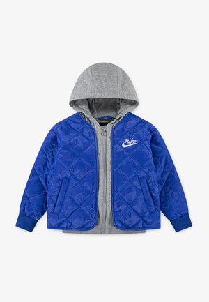 Blau gestepptes Jackett mit grauem Kapuzen, durchgehendem Reißverschluss, Seitentaschen und weißem Nike-Logo auf der Brust. Weiche Textur.
