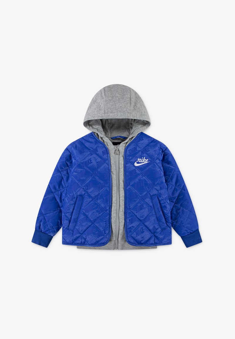 Niebieska pikowana kurtka z szarym kapturem, zapinana na zamek z przodu, z bocznymi kieszeniami i białym logo Nike na piersi. Miękka tekstura.