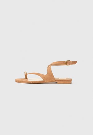 Tan suede sandal with an open toe, a curved design, ankle strap with gold hardware, and a flat sole. Smooth texture throughout.