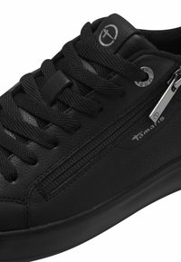 Sneakers en cuir noir avec un dessus texturé, fermeture à lacets, détail de fermeture éclair sur le côté et accent logo subtil. Semelle en caoutchouc pour adhérence et durabilité.