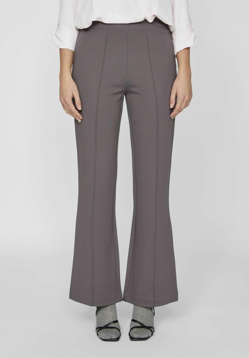 Pantalones acampanados de tejido suave y elástico en color gris tenue, con una cintura alta y costuras verticales prominentes para un aspecto ajustado.