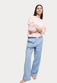 Rosa sweatshirt med vit grafisk design, parat med ljusblå randiga pyjamasbyxor. Bekväm passform, mjukt tyg och avslappnad stil.