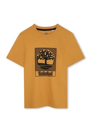 T-shirt jaune moutarde en coton, avec un graphique d'arbre noir à l'intérieur d'un carré et le mot "Timberland" en bas. Col rond.