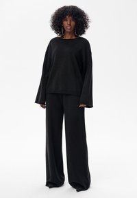 Czarny zestaw sweter z dzianiny i spodnie o szerokich nogawkach. Miękka tkanina, luźny krój, szerokie rękawy i okrągły dekolt. Gładka faktura, minimalistyczny design.