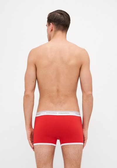 Red boxer briefs with a white waistband featuring "DSQUARED2" logo, snug fit, smooth texture, and contrasting white trim along the legs.