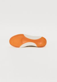 Schuhsohle mit einem orangefarbenen Gummibereich und weißen strukturierten Rillen. Verfügt über ein sechseckiges Muster und eine eingeprägte Markenbezeichnung. Glatte und langlebige Optik.