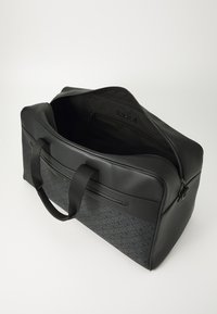 Black synthetic travel bag with zip closure, top handles, and a textured patterned lower section. Spacious interior with hidden pocket.