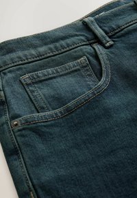 Tumši zilas džinsa bikses ar aizmugurējo kabatu, kurā redzams izšuvums un metāla kniedes, klasiskā griezuma, ar gludu tekstūru.