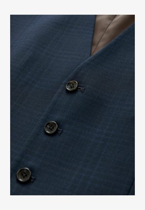 Giacca da completo blu navy in tessuto strutturato, con due bottoni neri e fodera interna marrone liscia. Leggero motivo a quadri visibile.