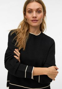 Must kampsun pikkade varrukatega, mille mansettidel ja kaelusel valged triibud. Pehme tekstuur, lõdvestunud lõikega disain.