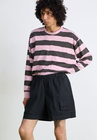 Long-sleeve pink and gray striped shirt with a crew neck paired with black elastic-waist shorts featuring side pockets and a textured finish.