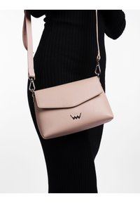 Růžová kožená crossbody taška s texturovaným povrchem, klopovým uzávěrem, stříbrným kováním a embosovaným logem značky na přední straně.