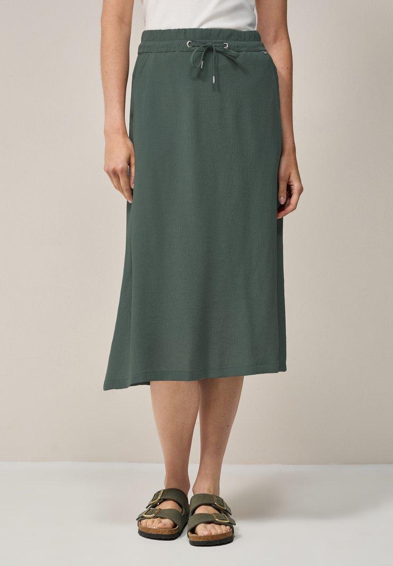 Groene midi-rok van textiel met een elastische tailleband, trekkoorddetail en een comfortabele pasvorm. Gecombineerd met bruine sandalen.